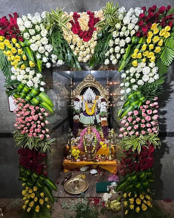 My work includes detailed floral adornment for temple deities. Here, a floral arch made of roses and chrysanthemums frames the idol, enhancing the sacred atmosphere.