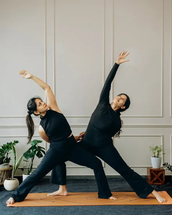 Two bodies, one rhythm. In partner yoga, every stretch is supported and every line is sharpened by alignment. Here, we explore a supported Trikonasana (Triangle Pose).