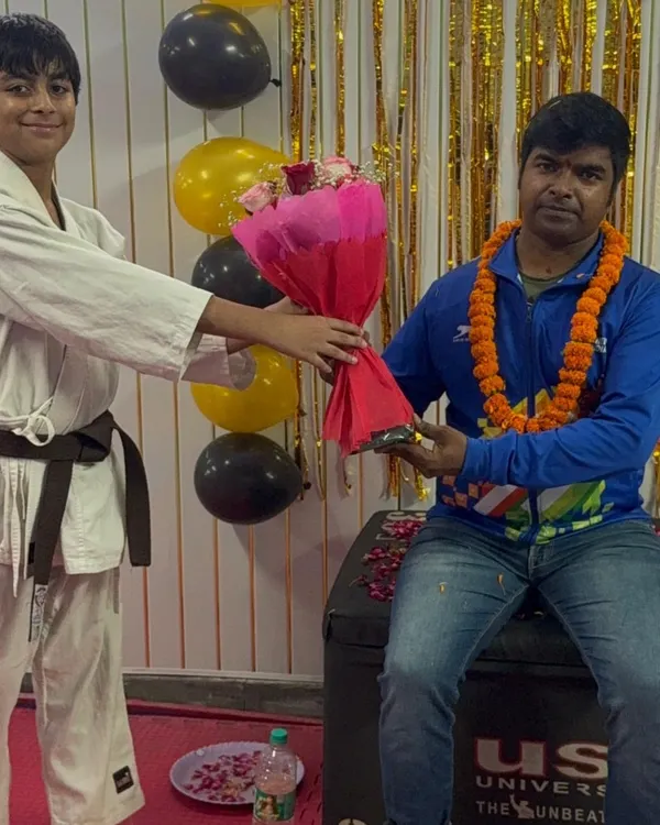 A student with a brown belt respectfully presenting flowers on Teacher's Day, showing the strong bond we build.