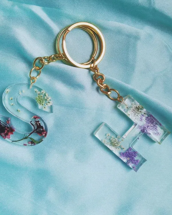 A beautiful pair of floral initial keychains, 'S' and 'H', made with different types of real pressed flowers. This shows how I can create a coordinated set for friends or couples, each with its own unique floral design.