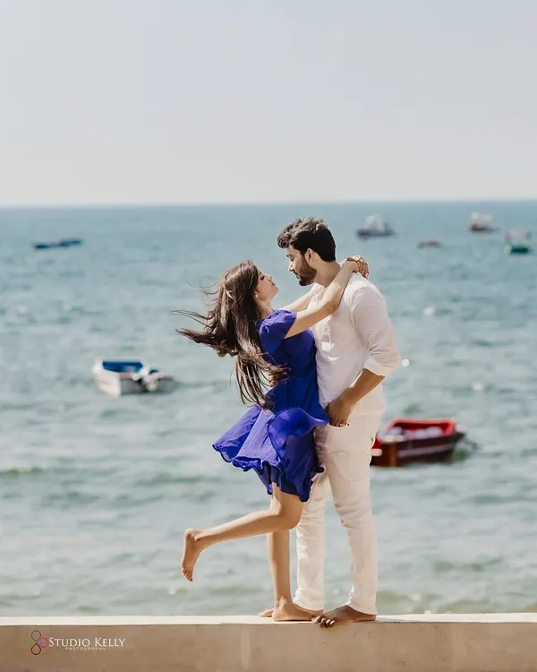 A breezy, romantic moment on the shores of Goa. The wind catching her hair and dress as they embrace by the sea creates a feeling of effortless, natural love.