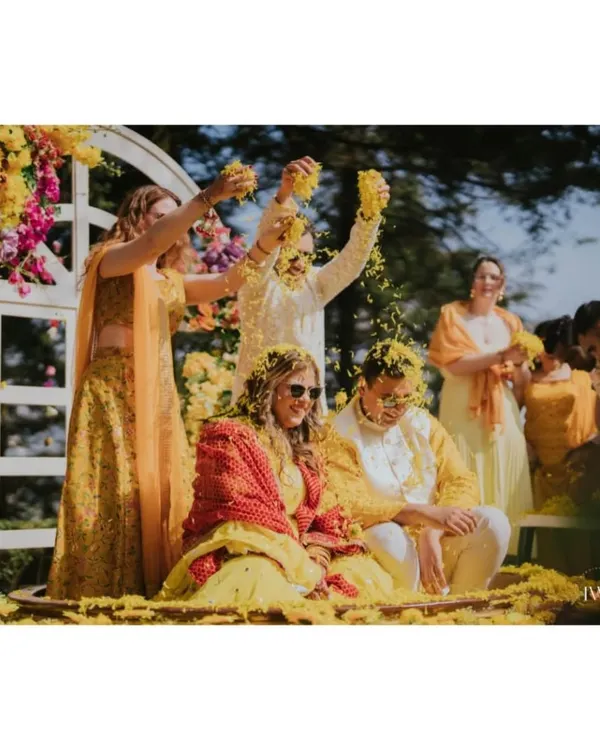 A shower of sunshine and marigolds. The couple is covered in yellow petals during their Haldi ceremony, a moment of pure, unadulterated joy and laughter with their closest friends and family.
