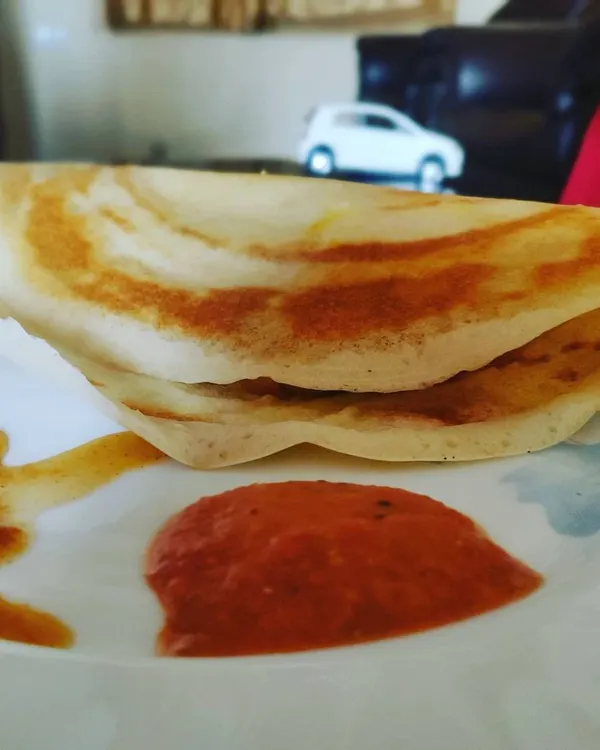 A classic plain dosa, cooked to a perfect golden-brown crisp and served with a side of spicy tomato chutney. A light yet satisfying meal.