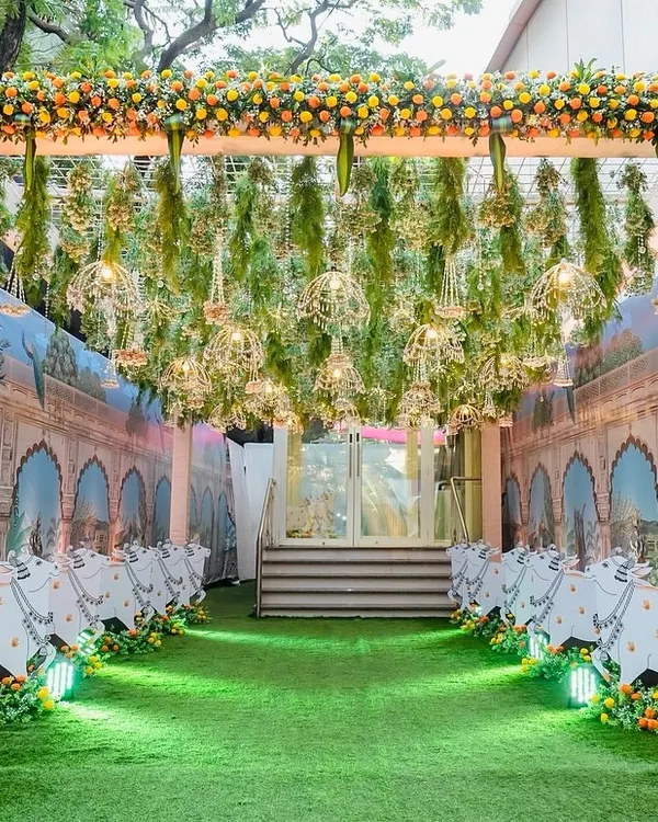 We created this immersive Pichwai-themed entrance for an event at Hiravati Banquet. The walkway is lined with custom cow cutouts against a backdrop of traditional Rajasthani art, while the ceiling is adorned with hanging floral arrangements and golden birdcages, guiding guests into a magical space.