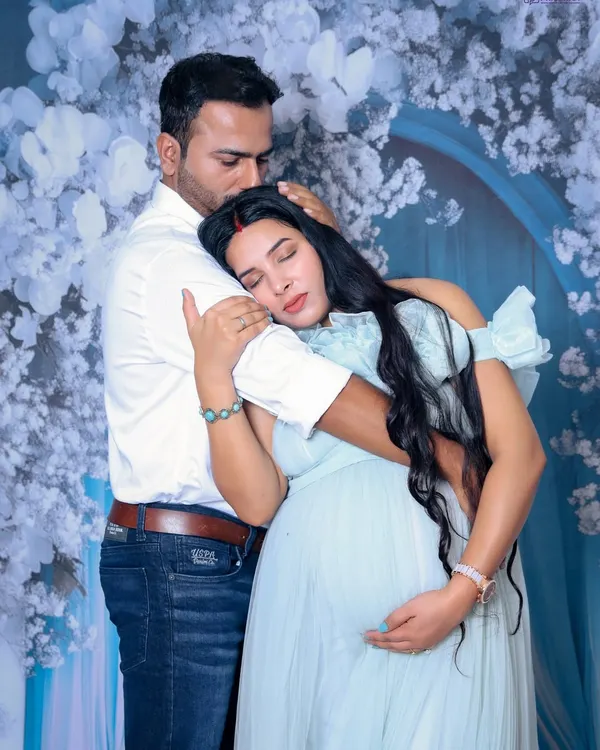 We focus on capturing the genuine emotion between you. This image shows a tender embrace, with the mother-to-be feeling safe and loved in her partner's arms, set against a soft, floral studio backdrop.