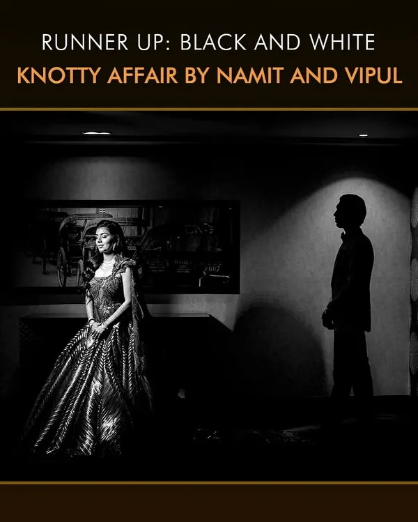 This award-winning black and white photograph is a study in light and shadow. The dramatic lighting creates a moody, cinematic feel, highlighting the bride's stunning gown and the groom's silhouette.