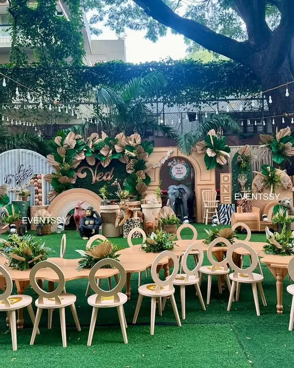 A full view of the 'Wild One' jungle party, complete with themed kid-sized tables and chairs set up on artificial turf for an immersive experience.