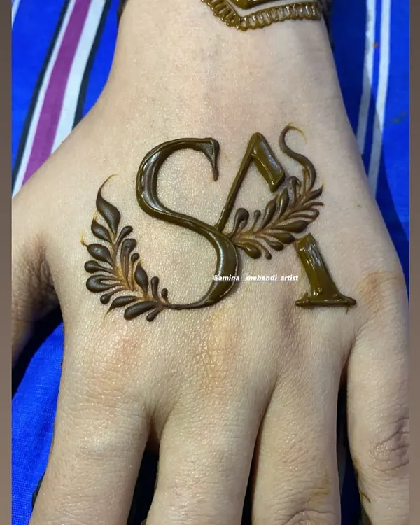A simple and elegant way to personalize your mehendi with initials. Here, the letters 'SA' are drawn in a beautiful script and adorned with delicate leaves.