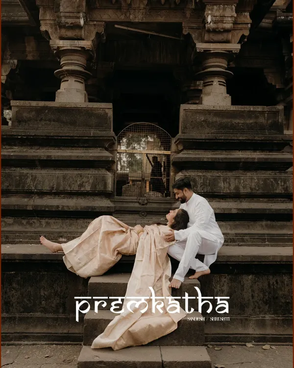 A 'premkatha' captured in stone and emotion. The couple shares a quiet moment on the steps of a historic temple, their traditional attire blending perfectly with the timeless surroundings.