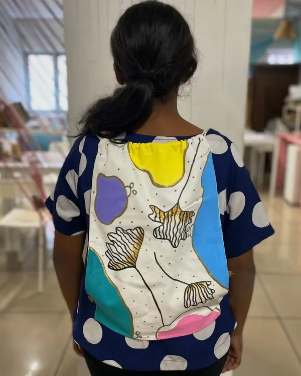 A participant modeling her beautifully hand-painted abstract backpack. Our backpack painting activity lets you create a stylish and necessary travel essential.