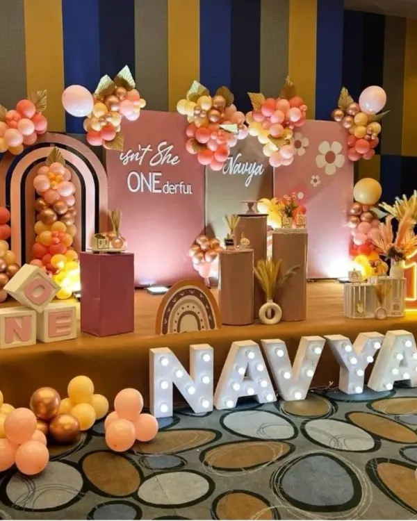A trendy "Isn't She ONEderful" themed first birthday with a warm, earthy color palette. This boho-chic setup features marquee letters, modern arched backdrops, and balloon clusters in shades of terracotta and rose gold.