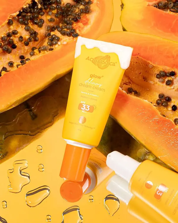 A vibrant shot for Aqualogica, using fresh papaya and a reflective surface to emphasize the product's natural ingredients and glowing effect.