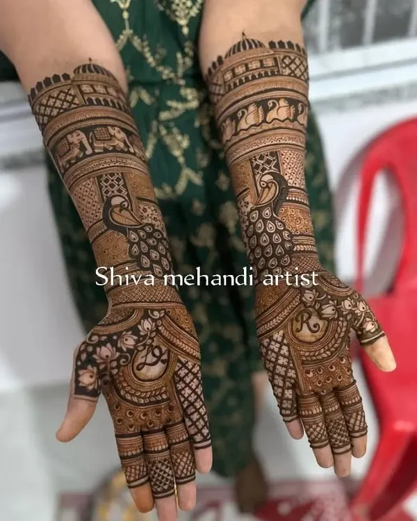 A beautiful example of traditional mehendi featuring majestic peacocks on the forearms. The palms have a delicate floral pattern with the bride's initial.