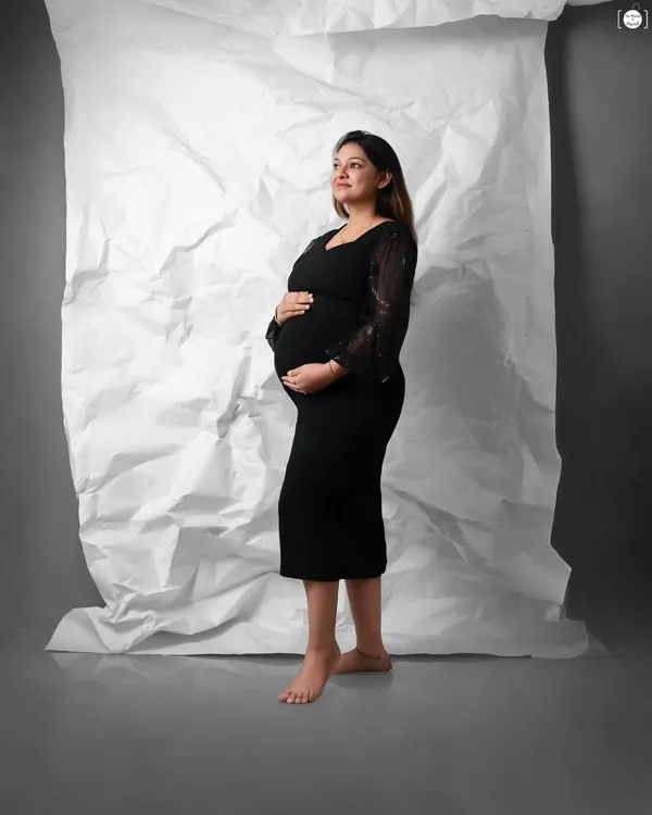 A timeless maternity portrait that will never go out of style. The combination of a simple black dress and a clean, textured backdrop creates a sophisticated and elegant look.