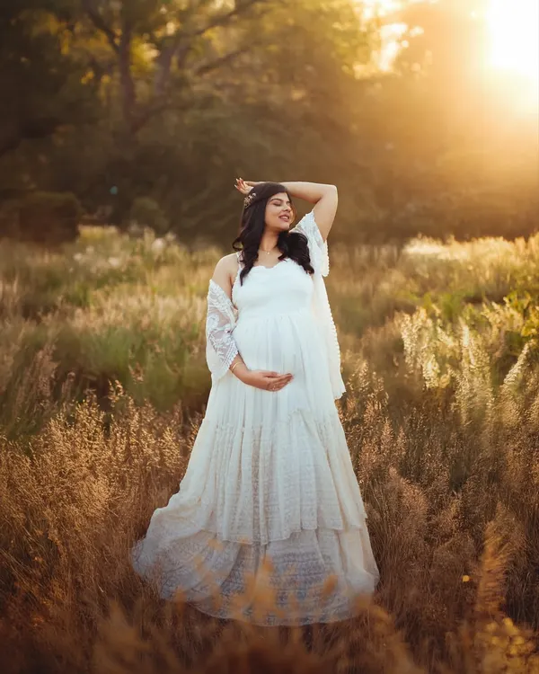 A solo portrait of the mom to be, basking in the warm glow of the setting sun. The flowing white gown and the natural field create a truly ethereal pregnancy photograph.