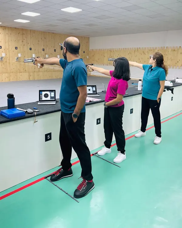 A family enjoys a session together at our indoor shooting range. Here, one of our certified coaches provides guidance on proper stance and aiming with an air pistol, ensuring a safe and memorable first time shooting range experience for all ages.