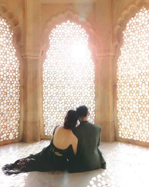 A quiet moment of togetherness framed by the intricate architecture of a palace. We specialize in creating these grand, cinematic shots that feel like they are straight out of a royal love story, focusing on the beautiful silhouette and the soft, natural light.