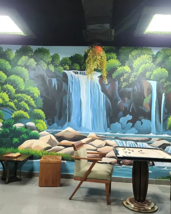 A serene waterfall mural painted in a recreational area at the Leela Ambience Hotel in Gurugram. This artwork transforms the room into a peaceful natural escape, perfect for relaxation.