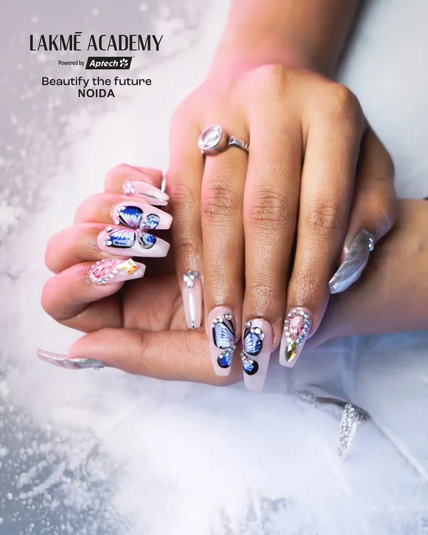 A close-up of long, coffin-shaped acrylic extensions featuring detailed butterfly wing art. Our students learn to build strong, elegant extensions and embellish them with multi-dimensional designs and rhinestones.