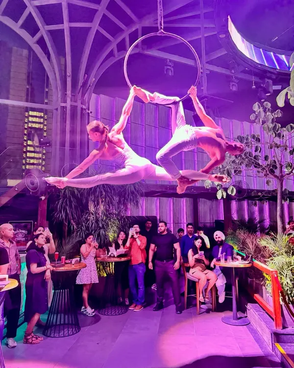 A powerful split pose during a live duo aerial hoop show. Working with a partner allows for stunning symmetrical shapes and a level of artistry that captivates any audience.