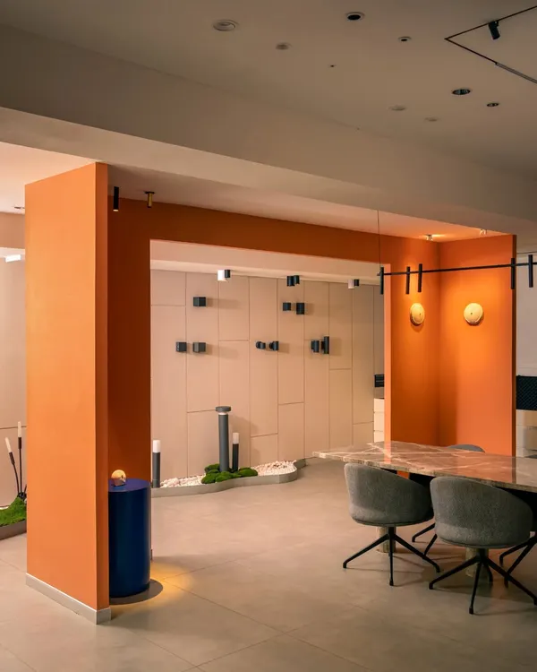 A wide view of the showroom, where a bold orange archway frames the main display area. This architectural feature adds a vibrant pop of color and helps to zone the space without using walls.