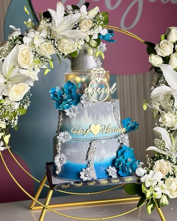 This blue and silver engagement cake, framed by a stunning arch of fresh white lilies and roses, is one of our absolute favorites. We designed it to be a true centerpiece, blending modern elegance with timeless romance to celebrate a beautiful new beginning.
