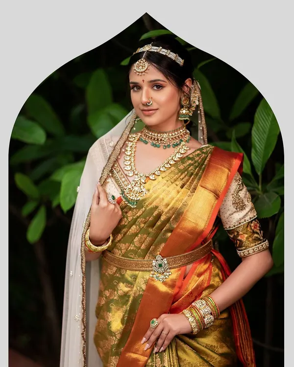 A vision of bridal splendor in an olive green and mustard Kanjeevaram silk saree. The ensemble is completed with a custom embroidered blouse, layered temple jewelry, and a delicate sheer veil for a touch of modernity.