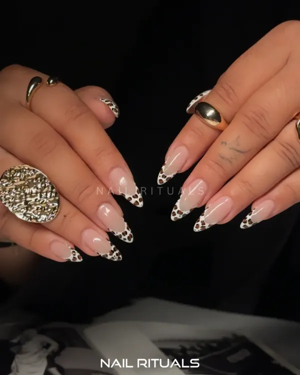 A modern twist on a classic. These almond-shaped nail extensions feature a chic cow print design on the French tips, giving a playful yet sophisticated finish to a nude manicure.