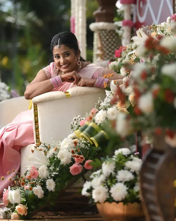 Dr. Namratha looking absolutely lovely during her ring ceremony. Seated amidst beautiful floral decor, her soft pink saree and fresh makeup look perfect for this happy, daytime occasion.