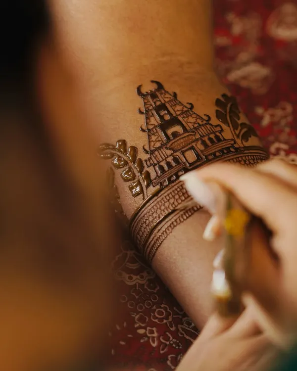 A close-up shot of me creating a detailed temple motif on a bride's arm. Every line is carefully drawn to ensure the final design is perfect.