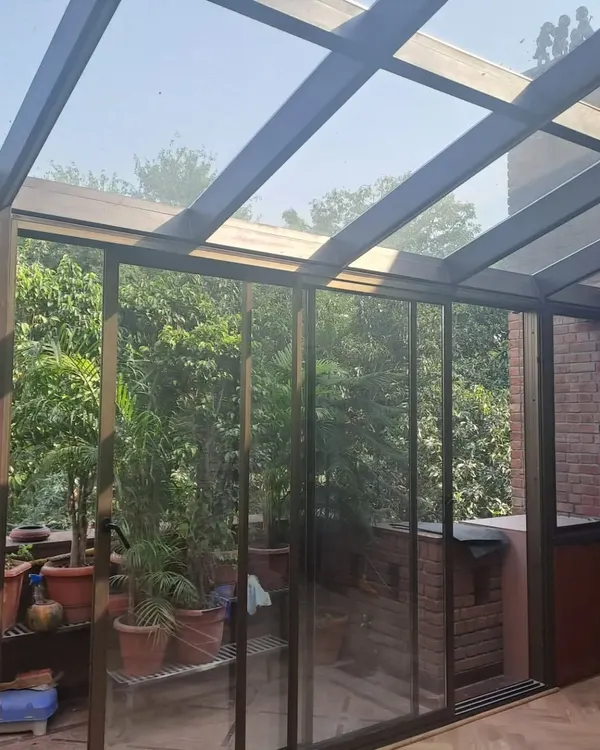 A completed glass sunroom that connects the main house to a terrace filled with plants. The sliding glass doors allow the space to be opened up completely, creating a true indoor-outdoor experience.