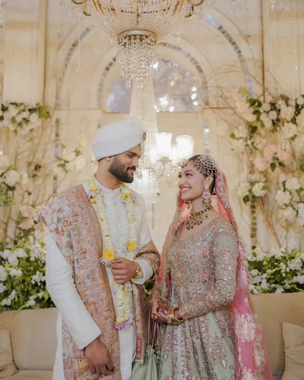 A beautiful moment captured in a stunningly decorated venue. The elegant white and floral backdrop, combined with a grand crystal chandelier, created a regal and romantic setting for this couple.