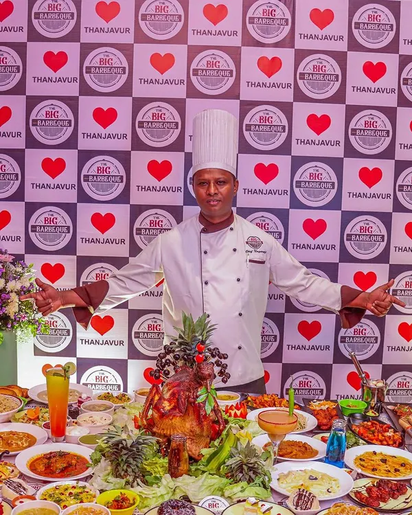 Our chef stands proudly behind a table overflowing with our signature dishes. This image captures the scale of our grand buffet, perfect for weddings, corporate events, and large family celebrations.