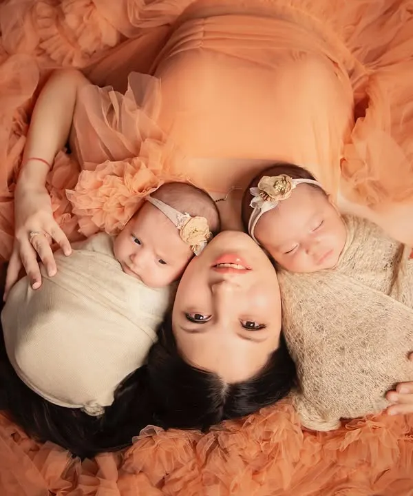 A mother's embrace with her two precious newborn twins. This artistic top-down shot, with the babies nestled in her beautiful gown, is a breathtaking portrait of motherhood.