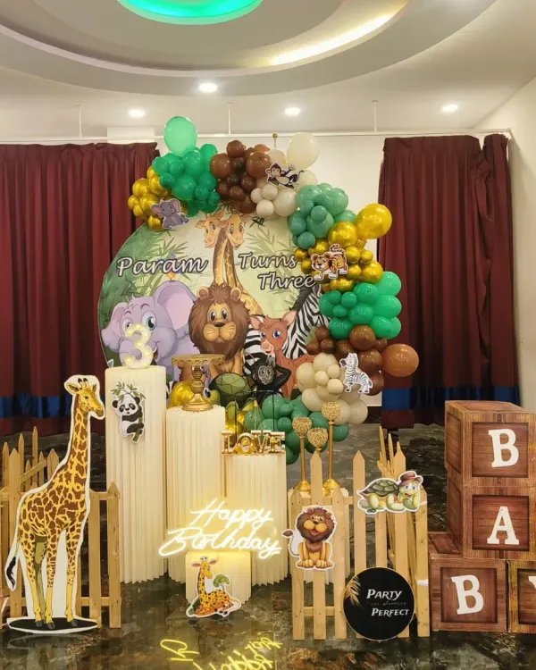 This full Jungle Safari theme is one of my specialties for kids' birthdays. The setup includes a custom printed backdrop featuring cartoon animals, an organic balloon arch in jungle colors, life-sized character cutouts like a giraffe, and illuminated 'BABY' blocks for that perfect photo opportunity.