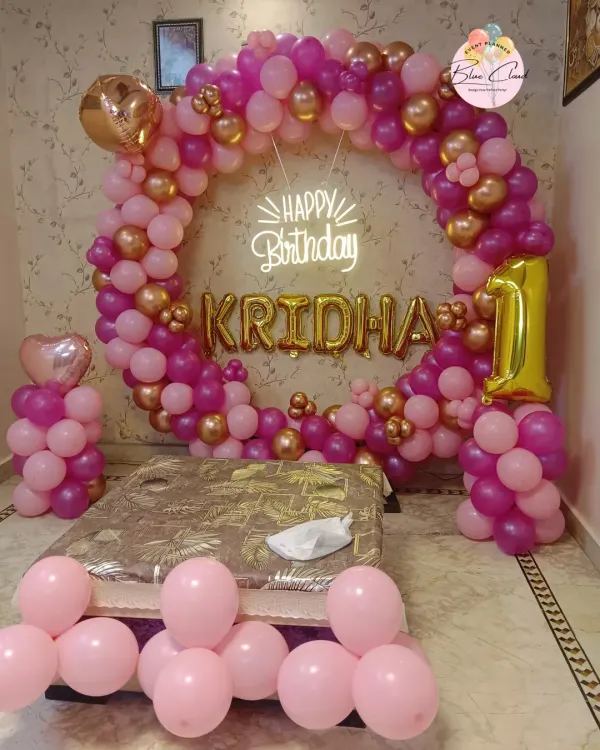 An elegant balloon ring decoration for a first birthday at home. We used shades of pink and gold to create this beautiful photo backdrop behind the cake-cutting area.