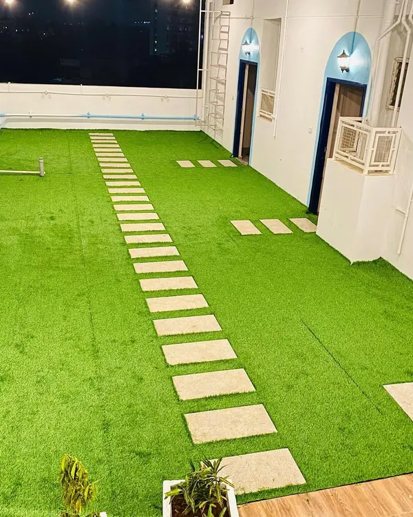 A wide view of the rooftop cafe project, showing the expansive area covered with our artificial turf. We integrated a long stone pathway for foot traffic, ensuring durability and design cohesion.