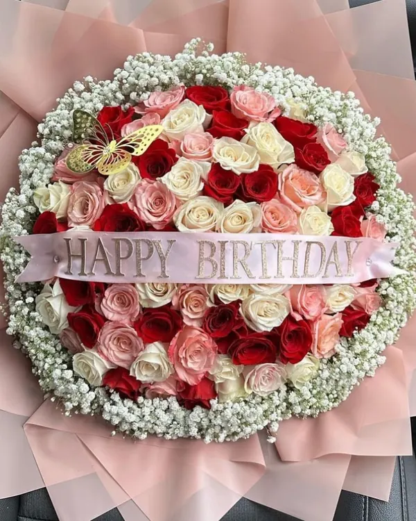 A grand, lush bouquet of red, pink, and white roses, encircled by delicate baby's breath and wrapped in soft pink paper. The custom "Happy Birthday" ribbon adds a personal touch to this extraordinary floral gift.