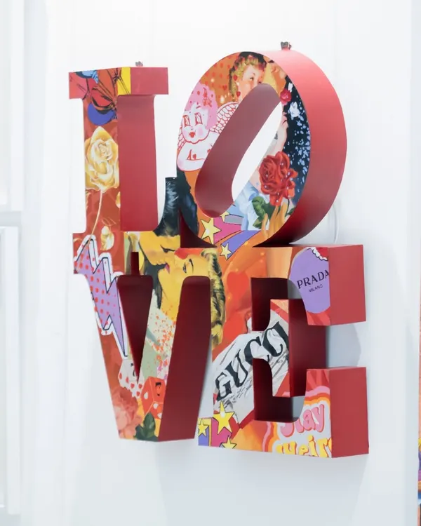 'Love Unleashed' by Khushi Gursale & Sarvesh Chavan. This metal artwork reinterprets Robert Indiana’s iconic LOVE sculpture as a cut-out layered with a vibrant pop art collage of brands like Gucci and Prada.