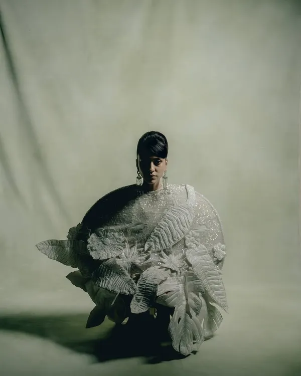 A moody, full-length portrait for Rahul Mishra, where dramatic shadows highlight the intricate, three-dimensional details of the white couture garment.