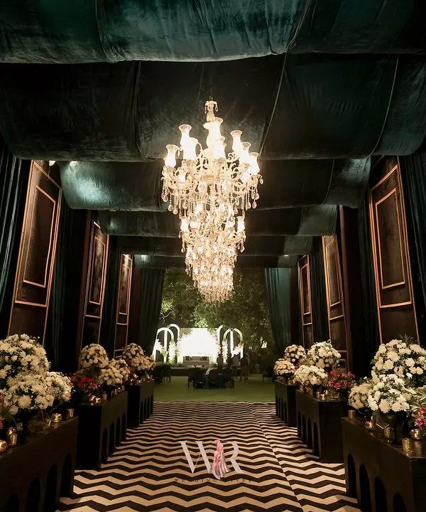 This is where the magic begins. We designed this grand, dramatic entrance with bold chevron flooring and deep velvet drapes, leading guests into an evening of glamour. The row of chandeliers creates a path of light, building anticipation for the celebration ahead.