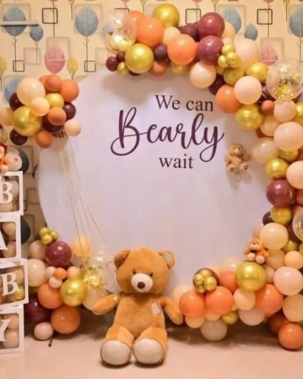 A 'We Can Bearly Wait' teddy bear theme for a baby shower. This setup includes a circular backdrop, a beautiful balloon arch in neutral colors, and cute teddy bear props.