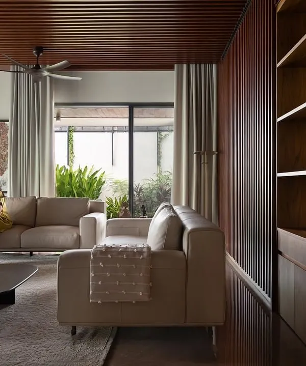 The formal living area in Villa Shakthi combines a warm wood-panelled ceiling with expansive windows, connecting the space to the lush landscape outside. We designed this room to feel both spacious and intimate, perfect for family gatherings or quiet reflection.