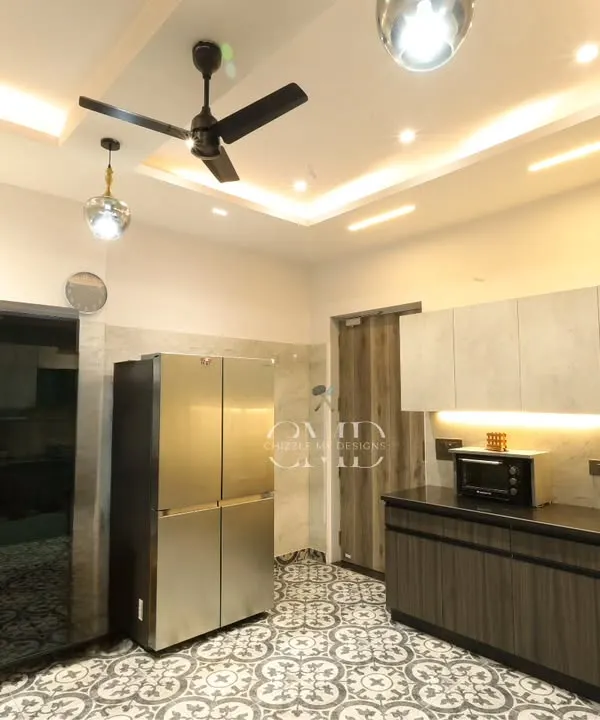 This monochrome-themed kitchen in Noida is a seamless blend of style and practicality, featuring patterned floor tiles and ample storage.