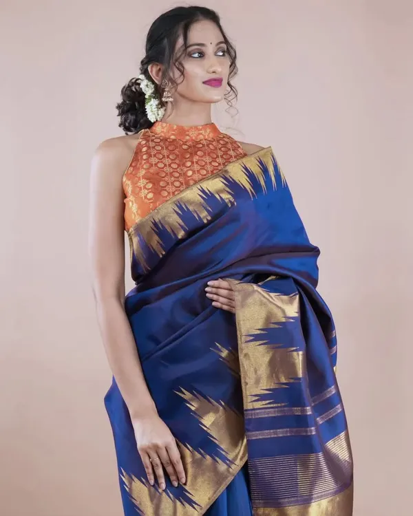 A chic halter-neck blouse in a vibrant orange brocade. This design is perfect for a modern ethnic look and can be paired with both sarees and skirts.
