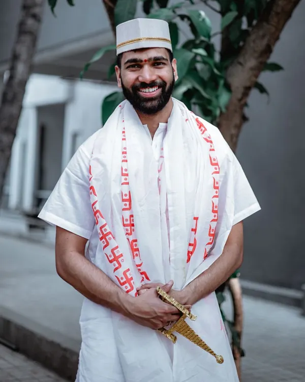 A smiling portrait of the groom during his Haldi ceremony, dressed in traditional white attire.