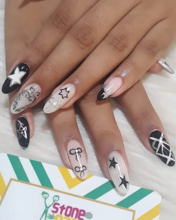 For those who love a bold look. This set features a mix of black and white gel polish with hand-painted stars, bows, and geometric patterns on long almond-shaped extensions.