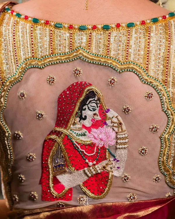 This bridal blouse is a canvas where stories are told in thread. The intricately embroidered depiction of a bride, set against a sheer back, is a hallmark of the personalized artistry I bring to your most special day.