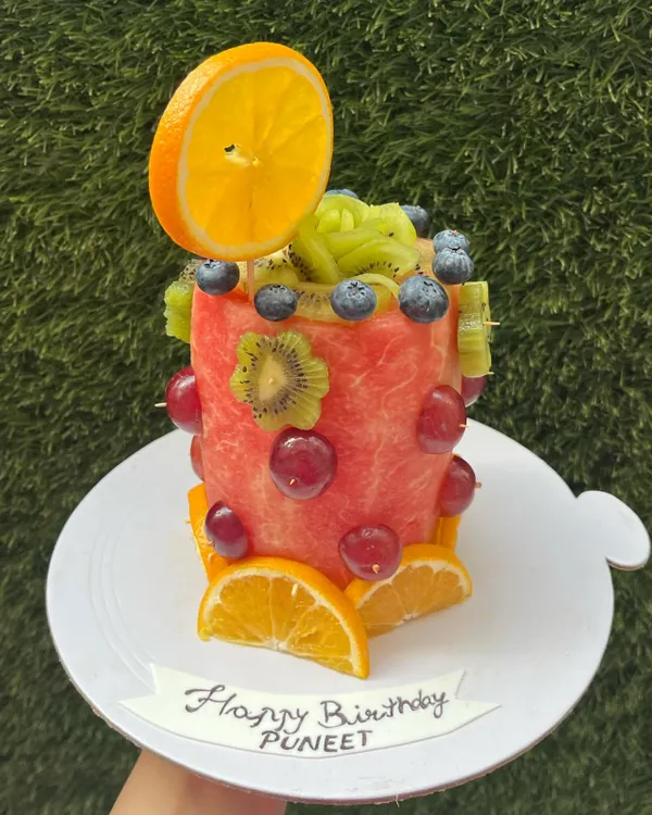 Our literal 'fruit cake' is a fun and unconventional centerpiece for any summer party. This one is carved from a watermelon and decorated with fresh kiwi, grapes, and oranges.