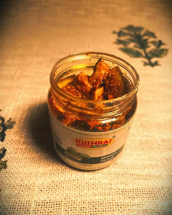 An open jar of my signature Mango Pickle. You can see the generous chunks of mango soaked in kacchi ghani oil and spices, a testament to its authentic, homemade quality.